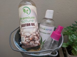 castor oil, aloe vera gel, and spray bottle in a bucket