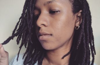 Girl in stripped shirt examining shoulder length locs
