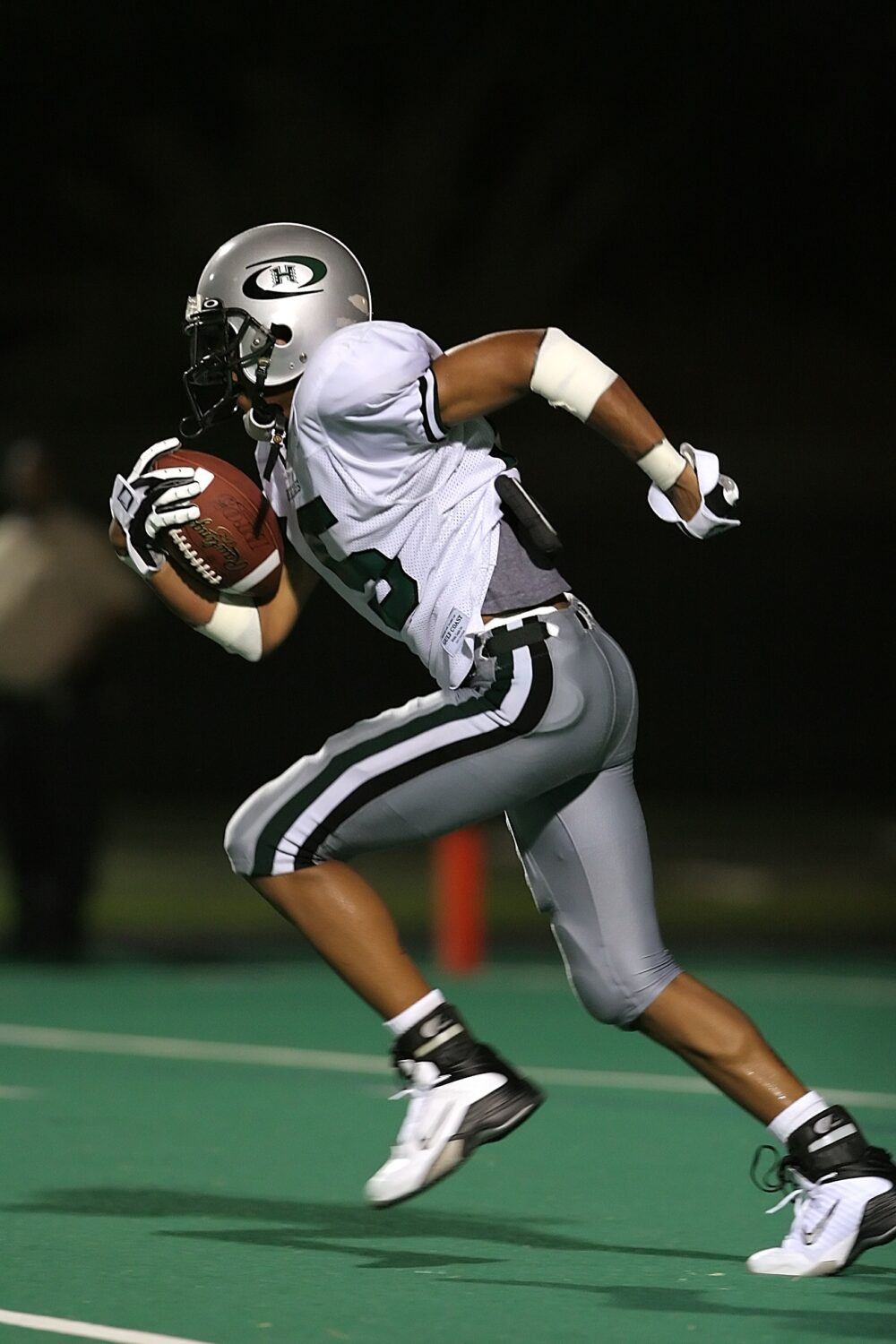 Why Do So Many NFL Players Have Locs? stock image of footballer running with a football